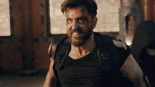a man with a beard is wearing a black tank top and a black backpack
