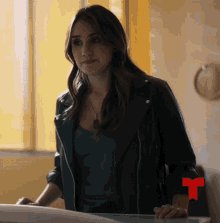 a woman in a black leather jacket with a red t on her sleeve
