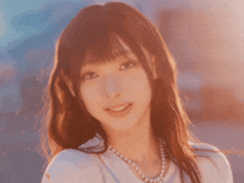 a woman wearing a white shirt and a pearl necklace looks at the camera