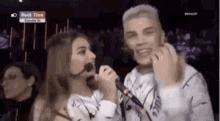 a man and a woman are singing into microphones in a dark room .