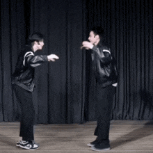 two men are dancing on a stage with a black curtain in the background
