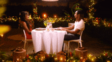 a man and a woman are sitting at a table with candles
