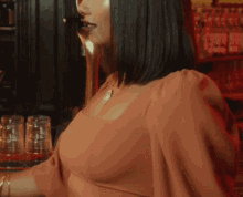 a woman wearing a necklace with a circle on it is standing in front of a bar