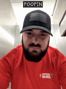 a man wearing a hat and a red shirt with the word poopin on it