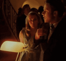 a woman standing next to a man holding a lamp in a dark room
