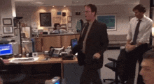 a man in a suit and tie stands in an office