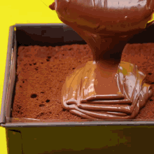 chocolate is being poured into a square pan of brownies
