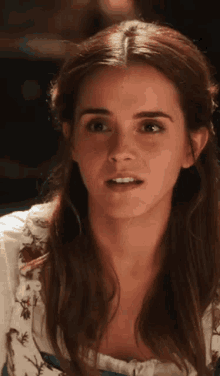 a close up of a woman 's face with long hair and a white top .