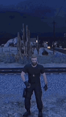 a man in a black shirt and black pants is standing in front of a cactus in the desert