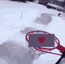 a basketball hoop in the snow with a heart in the net