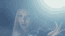 a woman is standing in a foggy room with her hands out .