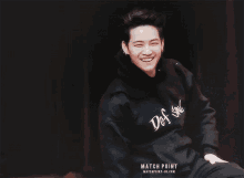 a young man wearing a black hoodie is smiling and laughing .