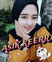 a woman wearing a black hijab and a yellow shirt has a sticker that says asik keerr on it