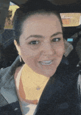a woman with a nose ring is smiling while sitting in the driver 's seat of a car