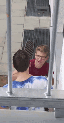 a man in a red shirt is talking to a man in a blue shirt