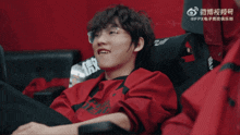 a man in a red shirt is sitting in a chair with chinese writing on the back
