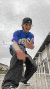 a young man wearing a blue shirt and black pants is giving a thumbs up .