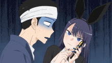 a man with a bandage on his head looks at a girl with bunny ears holding a cell phone