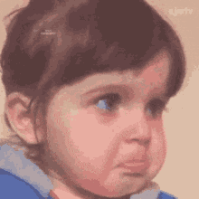 a little girl is making a sad face while wearing a blue jacket .