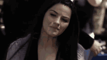 a woman with long black hair is sitting in a chair and talking to someone .