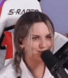 a woman is sitting in a chair with a microphone in front of her face .