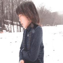 a woman in a striped sweater is standing in the snow