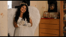 a woman in a white dress with angel wings holds a cup