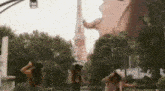a group of women are standing in front of a giant statue of a woman in front of a tower .