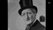 a black and white photo of a man wearing a top hat and bow tie with the svt logo in the corner