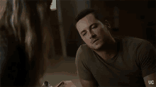 a man in a green shirt is looking at a woman with the letters uc on the bottom