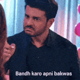 a man in a black suit is pointing at a woman with the words bandh karo apni bakwas written below him