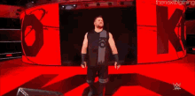 a wrestler is standing on a stage in front of a large screen .