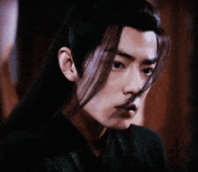 a man with long black hair is looking at the camera