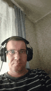 a man wearing a striped shirt and headphones looks at the camera