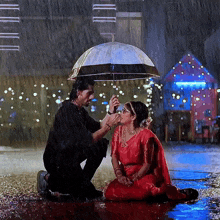 a man holds an umbrella over a woman kneeling down in the rain