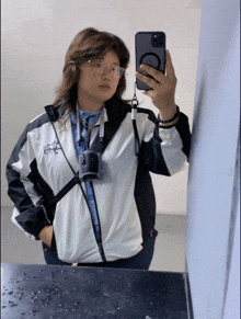a woman taking a picture of herself in a mirror with her phone