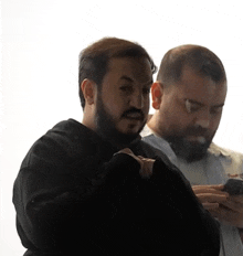 a man with a beard is looking at a cell phone