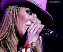 a woman wearing a purple hat is singing into a microphone with anahioverdose written below her