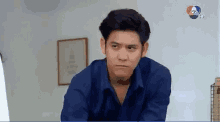 a man in a blue shirt is making a funny face and looking at the camera .