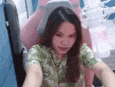 a woman in a green shirt is sitting in a pink chair .