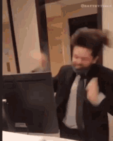a man in a suit and tie is dancing in front of a computer screen .