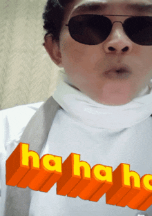a man wearing sunglasses and a white scarf has the word laugh on his shirt