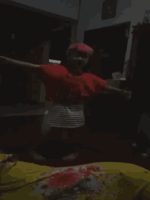 a little girl wearing a red shirt and a pink headband is dancing in a dark room