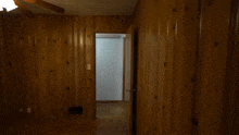 a man in a black shirt is standing in front of a wooden wall in a room .