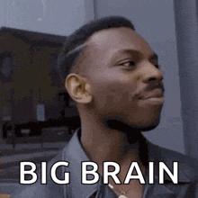a man in a leather jacket is looking up with the words `` big brain '' written on his forehead .