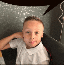 a young boy is sitting on a couch with his hand on his head