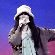 a woman singing into a microphone with foreign writing on the bottom right