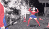 a woman in a red top and blue skirt is dancing in front of a fire .