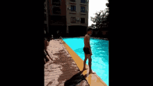 two men are jumping into a swimming pool and one of them is holding the other 's hand .