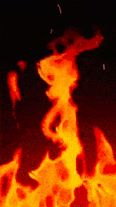 a close up of a fire with sparks flying in the dark